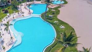Un complexe hôtelier doté d’une grande piscine sinueuse, d’espaces de détente situés au bord de la plage et offrant une vue sur l’océan.