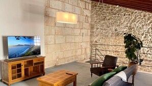 Un salon chaleureux avec un mur en pierre, un meuble TV en bois, un canapé et une table basse.