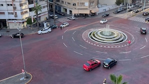 Una glorieta con una fuente central, rodeada de edificios de varios pisos con balcones.