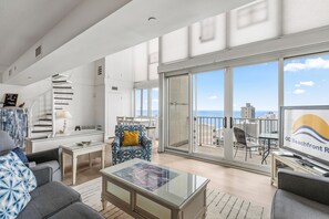 Un vaste espace de vie avec balcon, un escalier et une vue sur l’océan.
