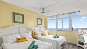 Ein Hotelzimmer mit zwei Betten, einem Deckenventilator, einem Fernseher und Blick aufs Meer.