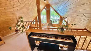 A wooden interior with a piano, wooden staircase, and potted plants. - Adventures On the lake / boat, cinema, spa, trails (Chute-Saint-Philippe)