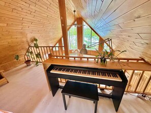 Een houten interieur met een piano, een houten trap en potplanten.