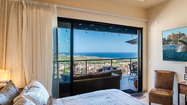 Une chambre avec un grand lit, un canapé, un fauteuil et une vue sur la mer.