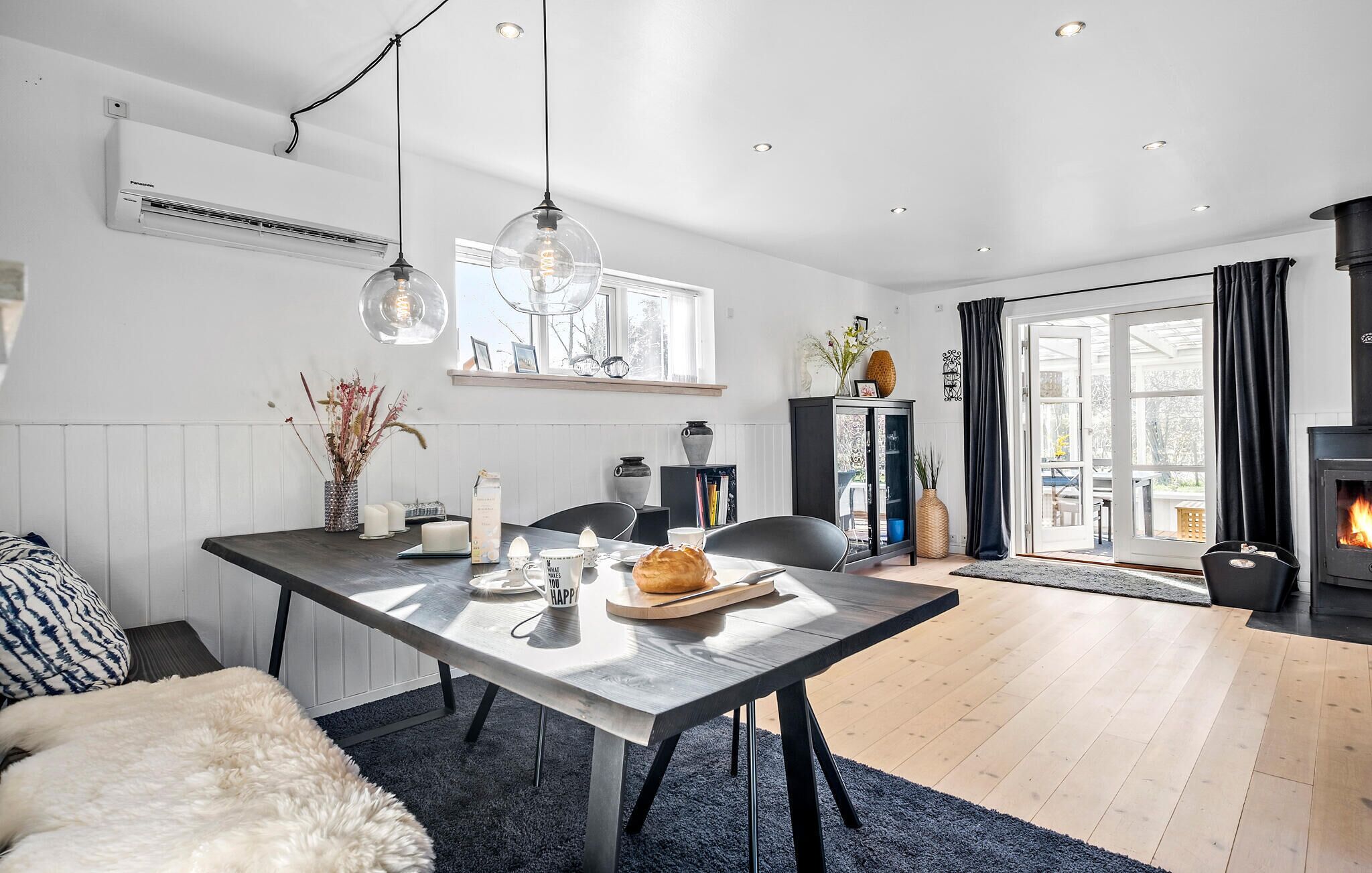 Une cuisine moderne avec une table à manger, des luminaires suspendus et une cuisinière intégrée.