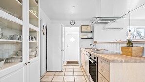 A modern kitchen with white cabinetry, a tiled floor, a wooden countertop, and a visible clock on the wall. - 3 bedroom stunning home in Højby (Højby)