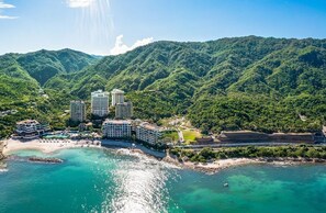A coastal resort with multiple high-rise buildings, a beach, and lush green hills in the background. - Award Winning 2-Bedroom Ocean View at Garza Blanca 5-Star Resort Puerto Vallarta (Puerto Vallarta)