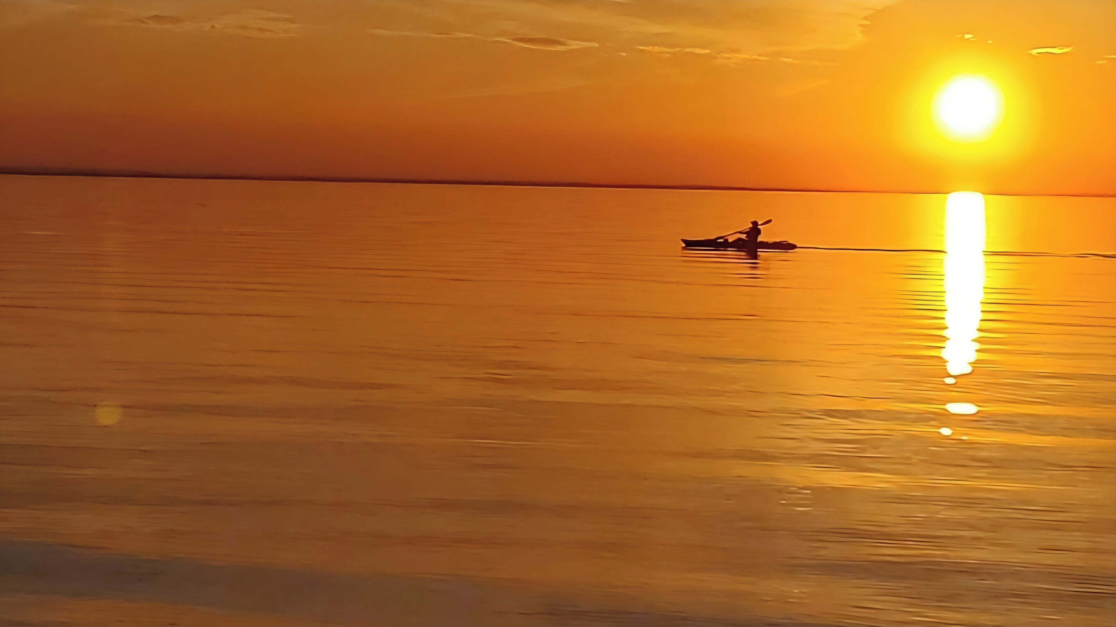 Une étendue d'eau calme, avec un bateau et une personne qui rame.
