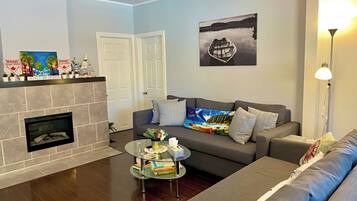 A living room with a fireplace, a sofa, a coffee table with books, and a painting on the wall.