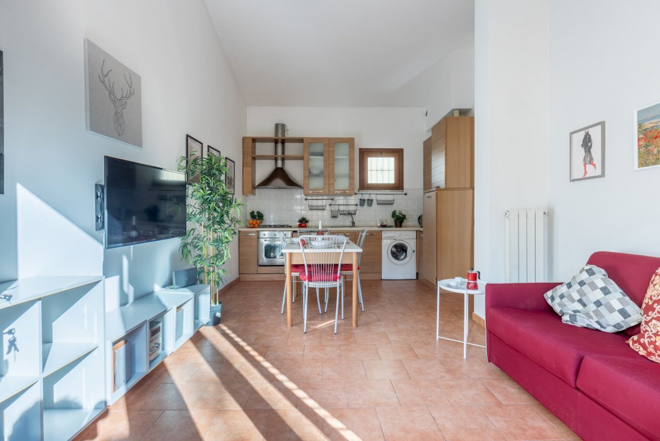 A compact living space with a kitchen, dining area, and a red sofa.
