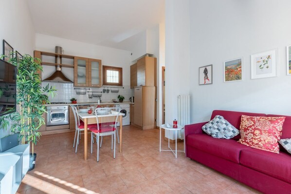 A compact living space with a kitchen, dining area, and a red sofa.