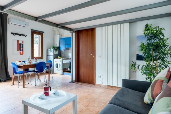 A modern living space with a dining area, kitchenette, and a sofa.