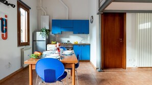 A kitchen with blue cabinets, a wooden table, and blue chairs. - GuestHost - Cozy studio apartment of about 50 sqm with mezzanine, located on the ground floor (one step at the entrance), able to comfortably accommodate up to 4 people. The accommodation is located in a quiet neighborhood, with all the main services. Wi (Pisa)