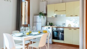 A modern kitchen with white cabinets, a built-in oven, and a dining area with a white table and chairs. - GuestHost - Cozy studio apartment of about 50 sqm with mezzanine, located on the ground floor (one step at the entrance), able to comfortably accommodate up to 4 people. The accommodation is located in a quiet neighborhood, with all the main services. Wi (Pisa)