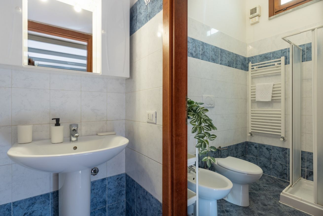 Ein Badezimmer mit Waschbecken, zwei Toiletten, einer Dusche und einem Spiegel.