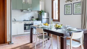 A modern kitchen with white cabinets, a dining table set for four, and a window with curtains. - GuestHost - Cozy studio apartment of about 50 sqm with mezzanine, located on the ground floor (one step at the entrance), able to comfortably accommodate up to 4 people. The accommodation is located in a quiet neighborhood, with all the main services. Wi (Pisa)