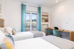 A modern bedroom with two beds, a desk, and a chair.