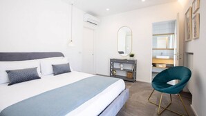 A modern bedroom with a large bed, bedside tables, a mirror, and a chair. - Modern Family Apt in Sorrento with Views (Sorrento)