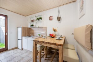 A compact kitchen with a refrigerator, sink, and wooden table set for dining.