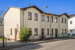 Ein mehrgeschossiges Wohngebäude mit flachem Dach, zahlreichen Fenstern und einem sichtbaren Eingang.