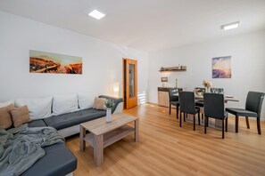 Ein modernes Wohnzimmer mit einer Couch, einem Couchtisch und einem Essbereich mit Stühlen und einem Tisch.