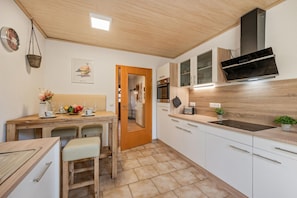 A modern kitchen with white cabinets, a wooden countertop, a built-in oven, and a black range hood.