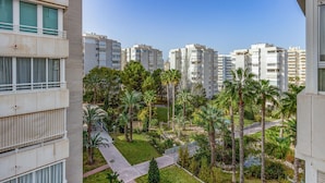 Un quartier résidentiel avec des immeubles d’appartements modernes, un jardin bien entretenu agrémenté de palmiers et un ciel dégagé.