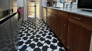 A kitchen with a black and white checkered floor, wooden cabinets, a stainless steel refrigerator, and a skylight above. - Cozy creekside home with deck, 15 min to airport, shopping, 1 hr to Crater Lk. 
 (Eagle Point)