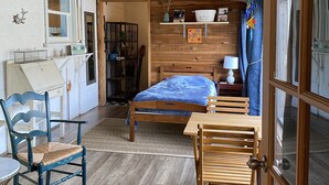 A cozy room with a wooden ceiling, a bed with a blue blanket, a wooden table, and a chair. - Cozy creekside home with deck, 15 min to airport, shopping, 1 hr to Crater Lk. 
 (Eagle Point)