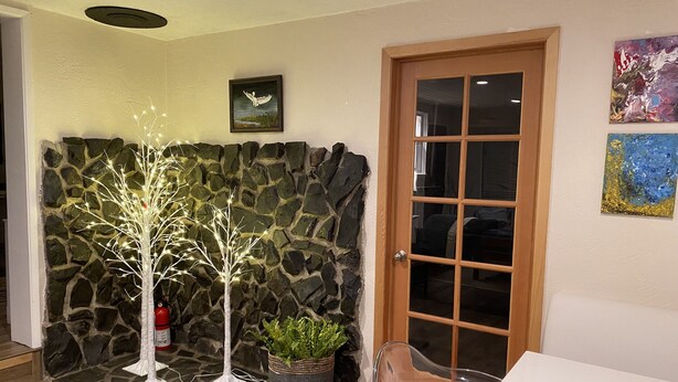 A room with a stone wall, a wooden door, a white table, and a potted plant. - Cozy creekside home with deck, 15 min to airport, shopping, 1 hr to Crater Lk. 
 (Eagle Point)