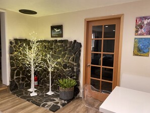 A room with a stone wall, a wooden door, a white table, and a potted plant. - Cozy creekside home with deck, 15 min to airport, shopping, 1 hr to Crater Lk. 
 (Eagle Point)