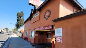 A motel with a prominent 'CARLOS MOTEL' sign, a 'MOTEL' sign, and a 'SE HABLA ESPAÑOL' sign indicating Spanish-speaking staff. - Carlo Motel (Los Angeles)