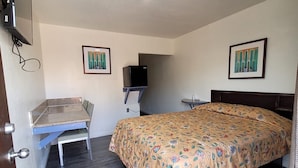 A bedroom with a bed, a desk, a chair, a television, and two framed pictures on the wall. - Carlo Motel (Los Angeles)