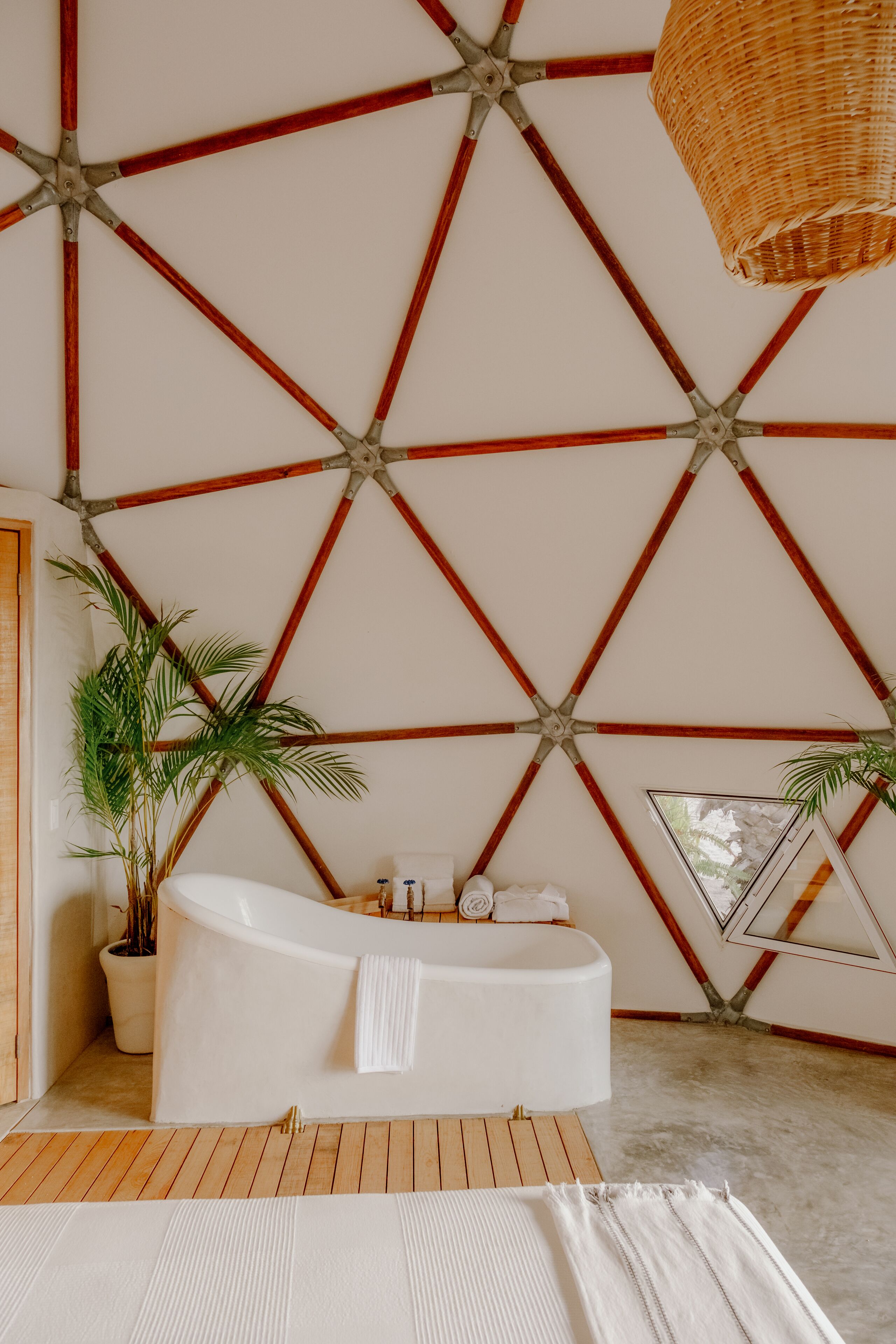 A modern bathroom with a freestanding bathtub, wooden flooring, and a geometric wall design.
