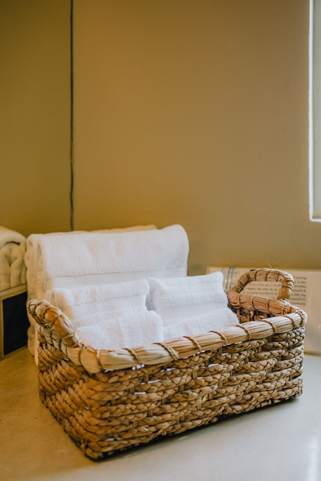 A wicker chair with a white towel draped over it, placed on a flat surface.