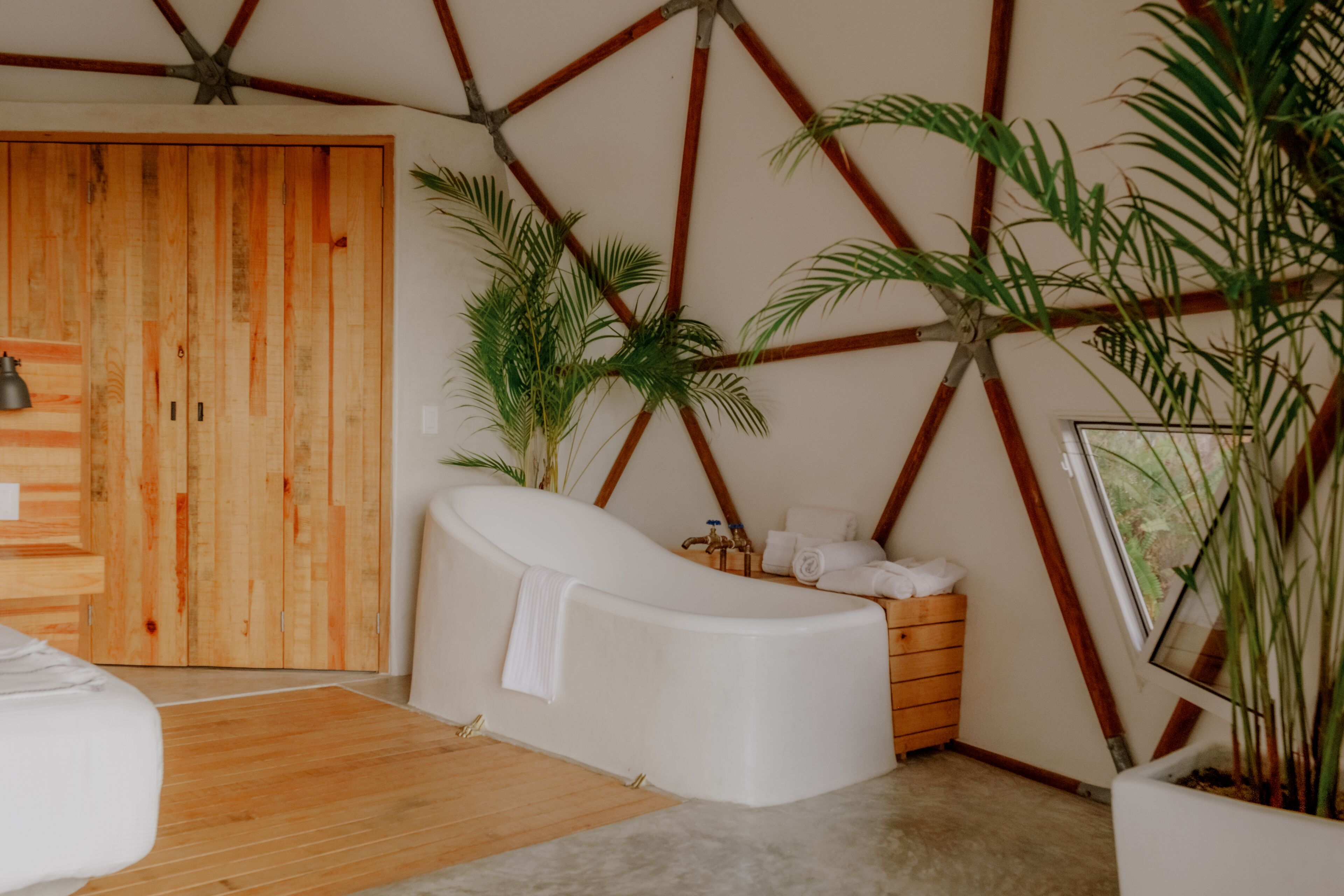 A modern bathroom with a wooden door, a freestanding bathtub, and a wooden cabinet.