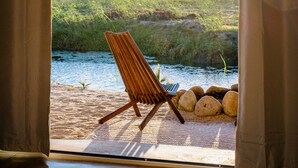 A beach chair facing a body of water with a grassy area and rocks in the foreground. - La Poza Boutique Hotel & Spa - Adults Only (Todos Santos)