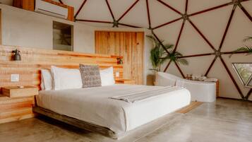 Een moderne slaapkamer met een houten hoofdbord, een groot bed met witte lakens, een nachtkastje en een ingebouwde bank.