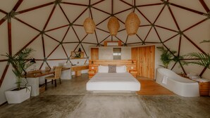 A modern bedroom with a geometric ceiling, a large bed, a wooden desk, and a bathtub. - La Poza Boutique Hotel & Spa - Adults Only (Todos Santos)