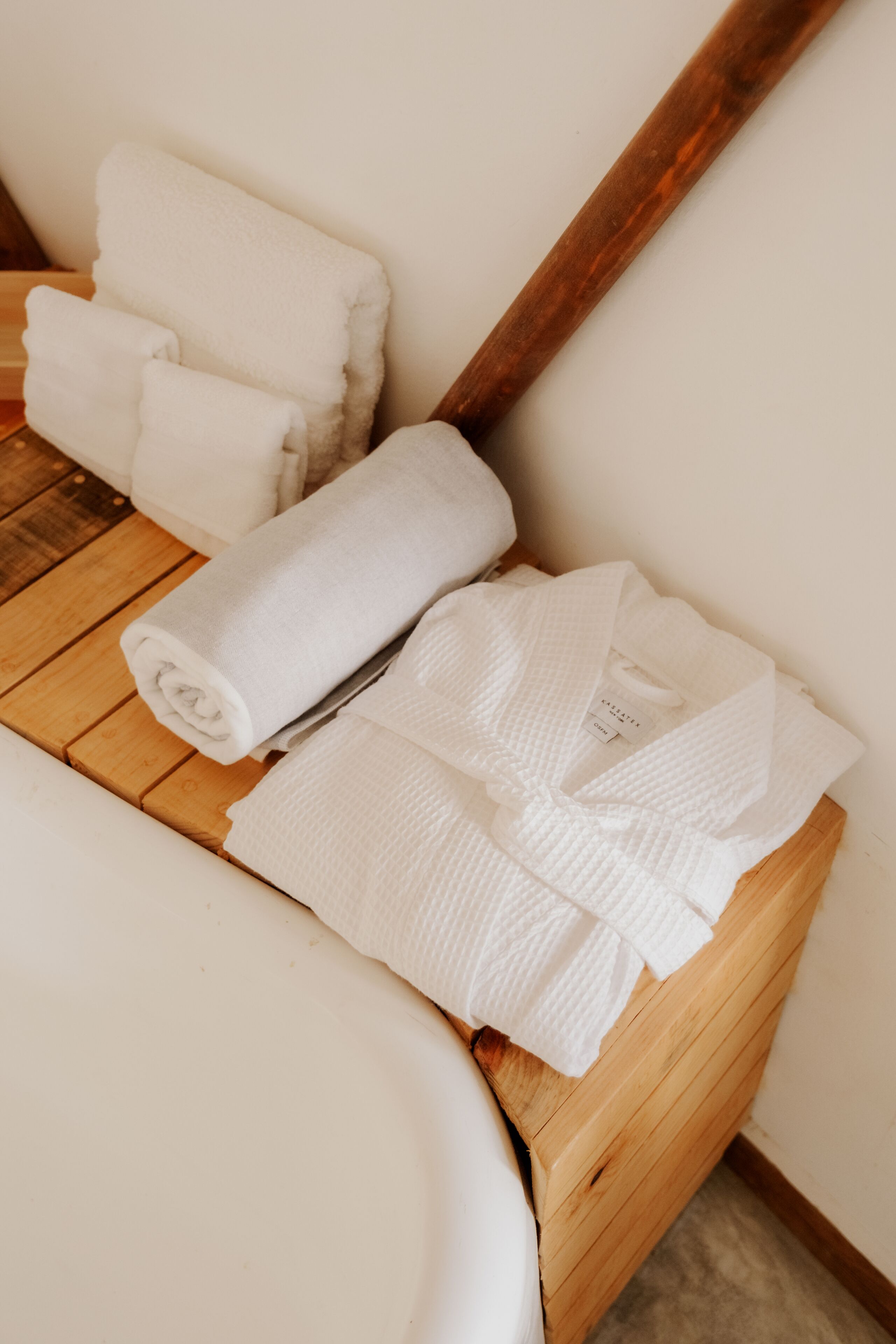 A wooden bench with white towels and a wooden stick leaning against a wall.
