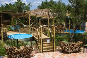 A pool area with a wooden deck, a pool, and a covered seating area. - Blue Sage No. 12 - The Long Loft Hideaway (Fredericksburg)