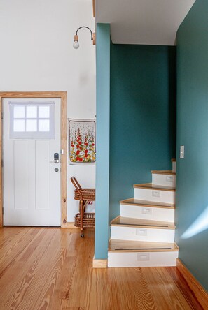 Una escalera de madera con paredes blancas que conduce a una habitación color aguamarina.