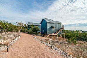 Un bâtiment doté d’un toit en métal et d’un escalier en bois menant à une terrasse.