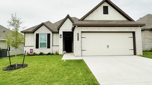 A two-story house with a garage, a small front yard, and a mailbox.
