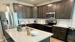 A modern kitchen with dark wood cabinets, stainless steel appliances, and a granite countertop.