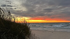 Ein Strand mit Wellen und einem Sonnenuntergang.
