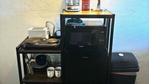 A compact kitchenette with a coffee maker, microwave, toaster, and storage shelves. - Studio Suite #38 River Front (Gold Beach)