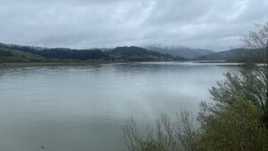 A calm lake with a forested shoreline and distant hills. - Studio Suite #38 River Front (Gold Beach)
