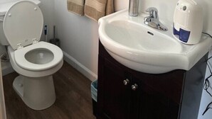 A bathroom with a toilet, sink, and towel rack. - Studio Suite #38 River Front (Gold Beach)