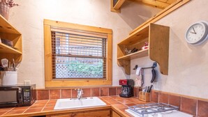 A compact kitchen with a window, wooden cabinets, a sink, a microwave, and a gas stove. - Homey Cabin with Jacuzzi Near Ski Apache (Ruidoso)